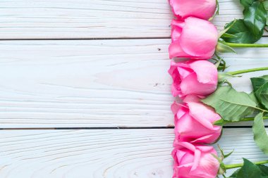 Ahşap arka plan üzerinde cam vazo içinde pembe Gül