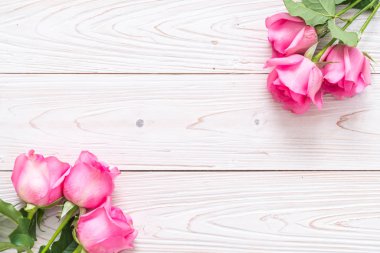 Ahşap arka plan üzerinde cam vazo içinde pembe Gül