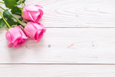 Ahşap arka plan üzerinde cam vazo içinde pembe Gül