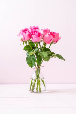 Ahşap arka plan üzerinde cam vazo içinde pembe Gül