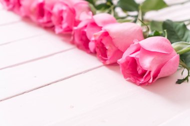 Ahşap arka plan üzerinde cam vazo içinde pembe Gül