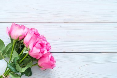 Ahşap arka plan üzerinde cam vazo içinde pembe Gül