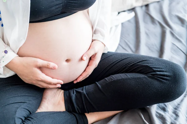 Vientre de la mujer embarazada con las manos — Foto de Stock