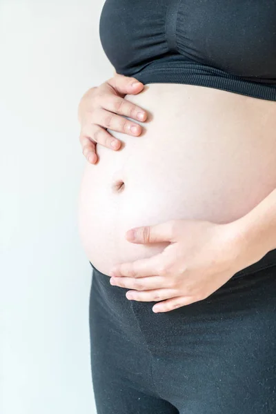 Vientre de la mujer embarazada con las manos — Foto de Stock