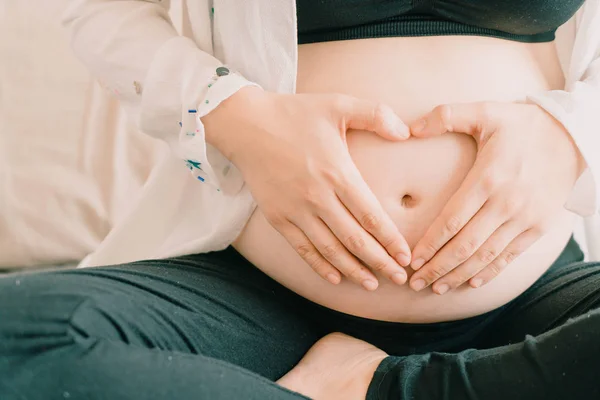 Joven hermosa asiática embarazada sosteniendo sus manos en un escuchar — Foto de Stock