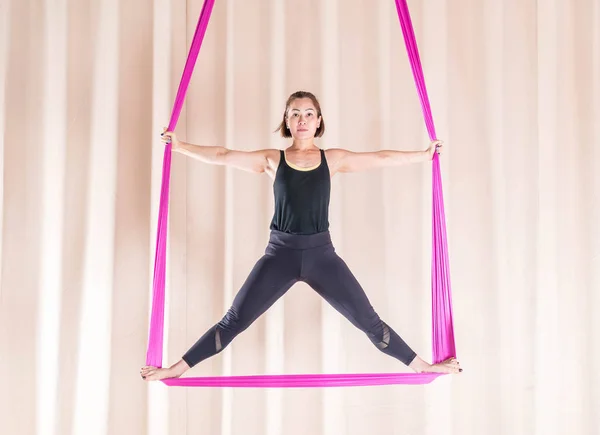 Asian woman training in fitness room with fly yoga elements — Stock Photo, Image