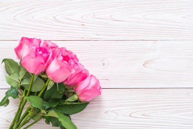 Ahşap arka plan üzerinde cam vazo içinde pembe Gül