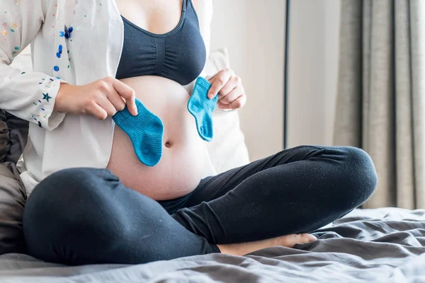 孕妇的腹部与手选择婴儿袜 — 图库照片