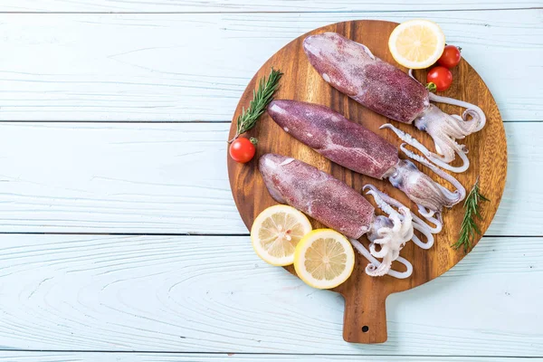 Fresh octopus or squids raw on wooden board — Stock Photo, Image