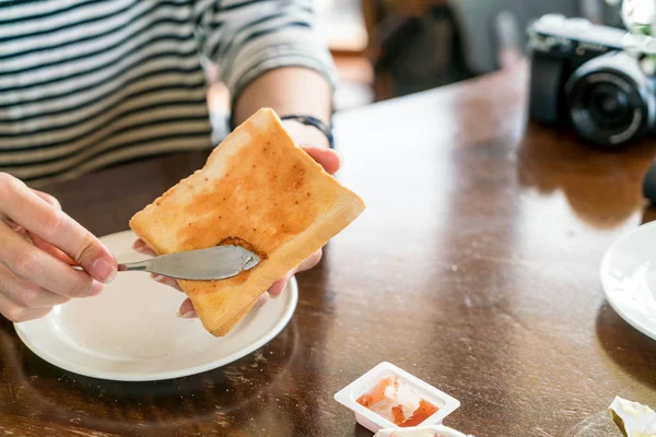 Рука с хлебом и клубничным вареньем на завтрак — стоковое фото