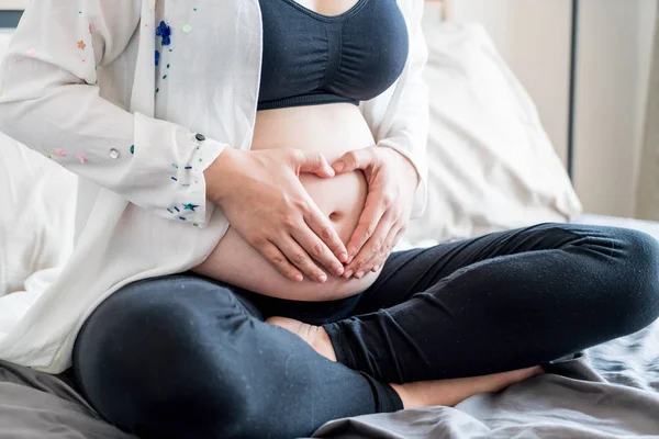 Joven hermosa asiática embarazada sosteniendo sus manos en un escuchar — Foto de Stock