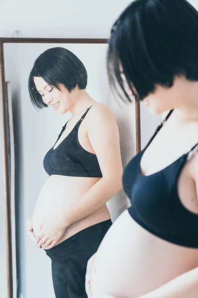 年轻美丽的亚洲孕妇抚摸她的腹部在家里 — 图库照片
