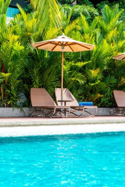 Şemsiye ve sandalye otel ve tatil yüzme havuzunda çevresinde 