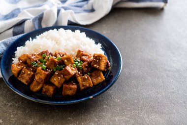 Baharatlı soslu Kızarmış tofu pirinç üzerine ilave edin.