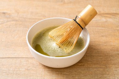 Yeşil çay tozu ve çırpılmış sıcak kibrit yeşil çay fincanı.