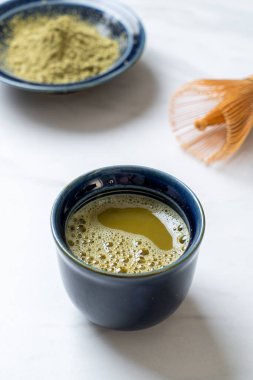 Yeşil çay tozu ve çırpılmış sıcak kibrit yeşil çay fincanı.