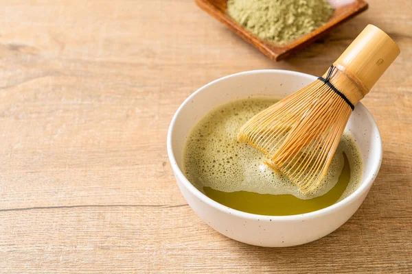 hot matcha green tea cup with green tea powder and whisk