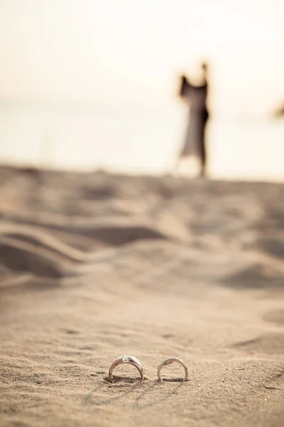 Кольца на пляже с невестой и женихом на заднем плане — стоковое фото