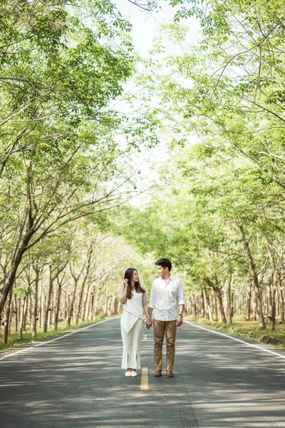 Счастливая азиатская пара влюбленная на дороге с дугой дерева — стоковое фото