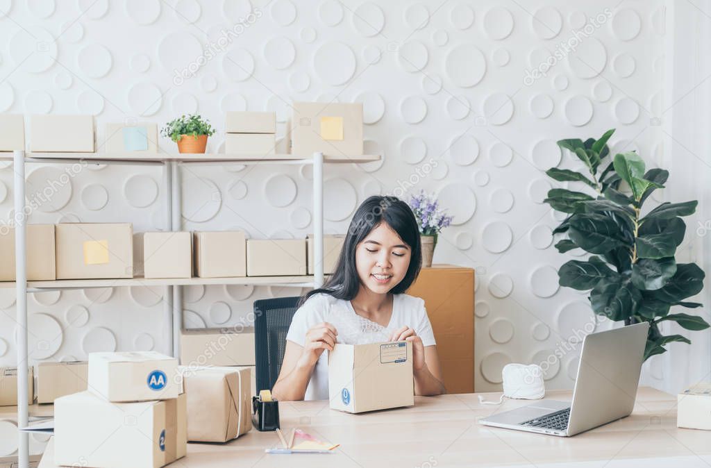 Asian Women business owner working at home with packing box on w