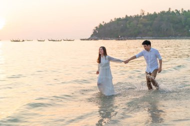 Mutlu çift balayı gidiş tropikal kum plajı üzerinde su içinde seyahat.