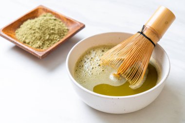 Yeşil çay tozu ve çırpılmış sıcak kibrit yeşil çay fincanı.