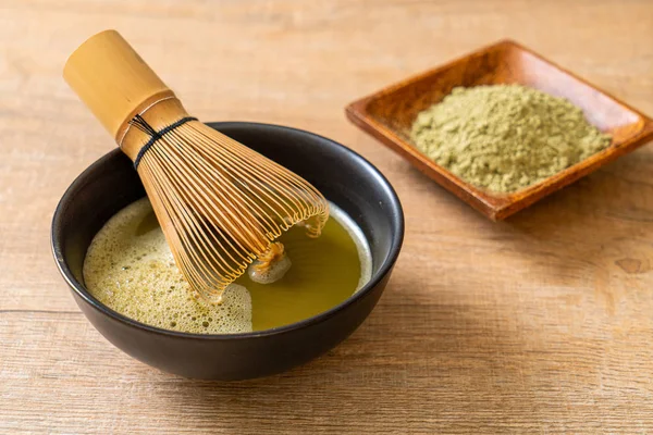 hot matcha green tea cup with green tea powder and whisk