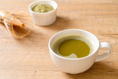 Yeşil çay tozu ve çırpılmış sıcak kibrit yeşil çay fincanı.