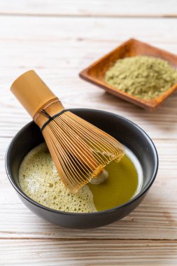 Yeşil çay tozu ve çırpılmış sıcak kibrit yeşil çay fincanı.