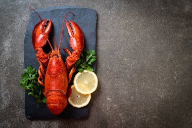 bitkisel ve siyah arduvaz plaka üzerinde limon ile ıstakoz