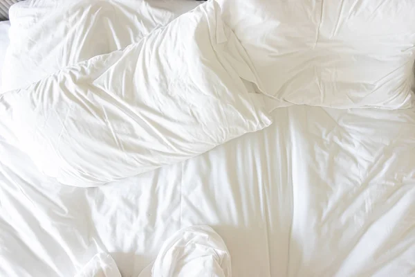 Белая подушка с одеялом на кровати — стоковое фото