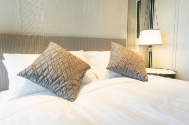 Yatak odasındaki beyaz yastıklar dekore edilmiş.