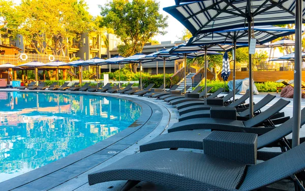 Bedpool with umbrella around swimming pool in hotel resort — Stock Photo, Image