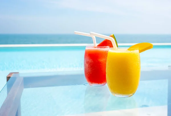 Mango smoothie and watermelon smoothie with swimming pool and se — Stock Photo, Image
