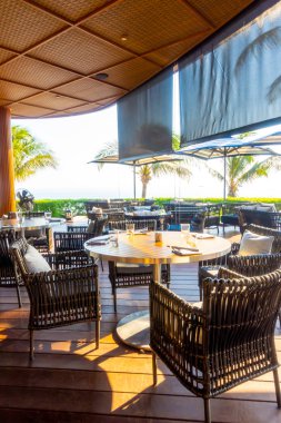 Açık teras güvertesi ve okyanus sahili arka planına sahip sandalye.