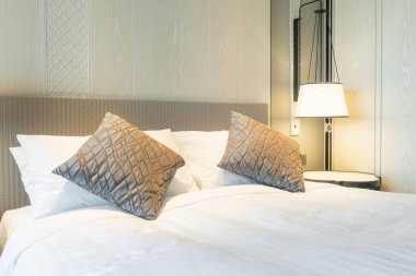 Yatak odasındaki beyaz yastıklar dekore edilmiş.