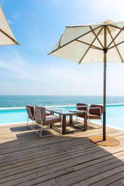 Güzel, boş bir sandalye ve yüzme havuzlu bir şemsiye.