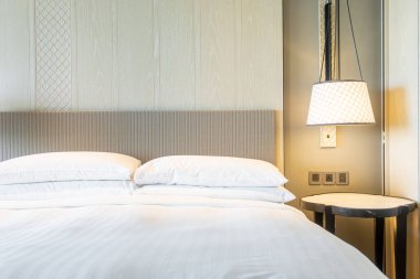 Yatak odasındaki beyaz yastıklar dekore edilmiş.