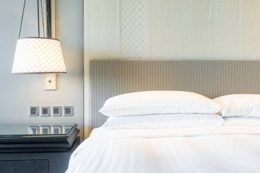 Yatak odasındaki beyaz yastıklar dekore edilmiş.