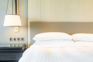 Yatak odasındaki beyaz yastıklar dekore edilmiş.