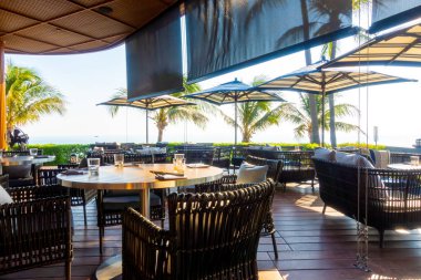 Açık teras güvertesi ve okyanus sahili arka planına sahip sandalye.