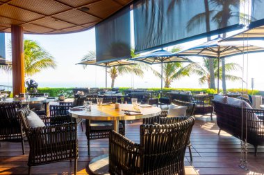 Açık teras güvertesi ve okyanus sahili arka planına sahip sandalye.