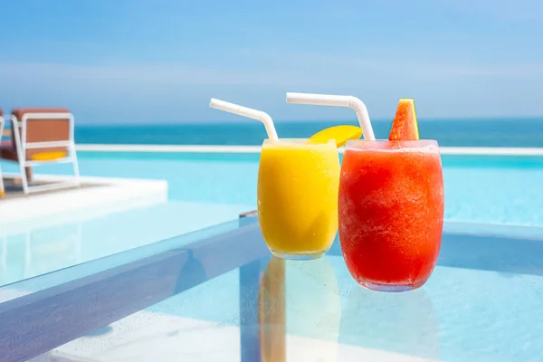 Watermelon smoothie and mango smoothie with swimming pool and se — Stock Photo, Image