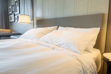 Yatak odasındaki beyaz yastıklar dekore edilmiş.