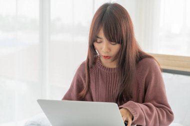 Asian women working with laptop on bed