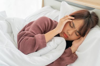 Asian women headache and sleeping on bed