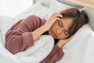Asian women headache and sleeping on bed