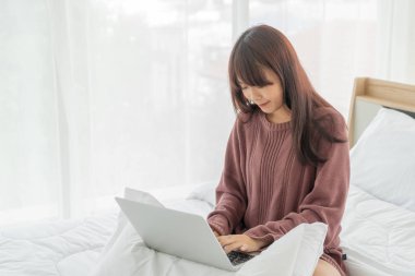 Asian women working with laptop on bed