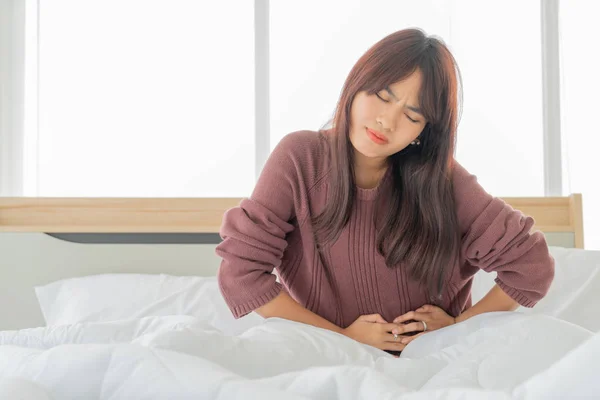 Wanita Asia sakit perut dan tidur di tempat tidur — Stok Foto