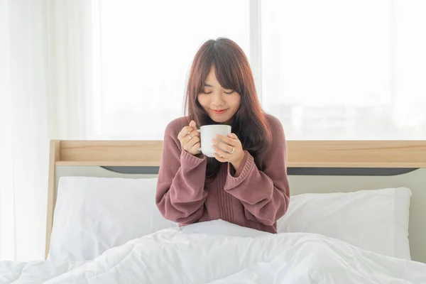 Asian women drinking coffee on bed in the morning — Stok fotoğraf